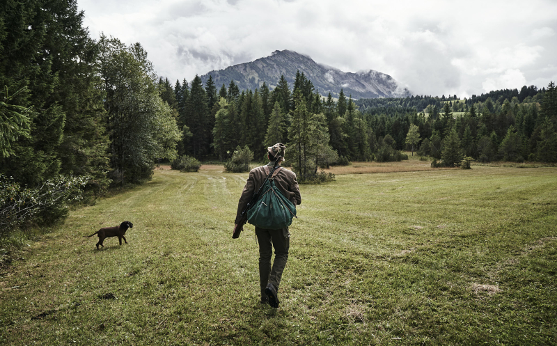Angebot im Wellnesshotel HUBERTUS - Wild trifft Wein Jäger spaziert über die Wiesen im Unterjoch - Angebot im HUBERTUS